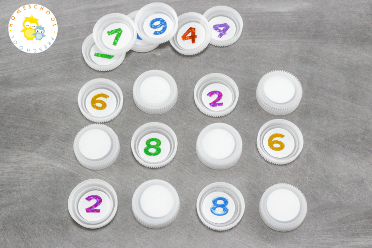Come discover how to set up a low prep math game for preschoolers. All you need is some number stickers and some plastic bottle caps.