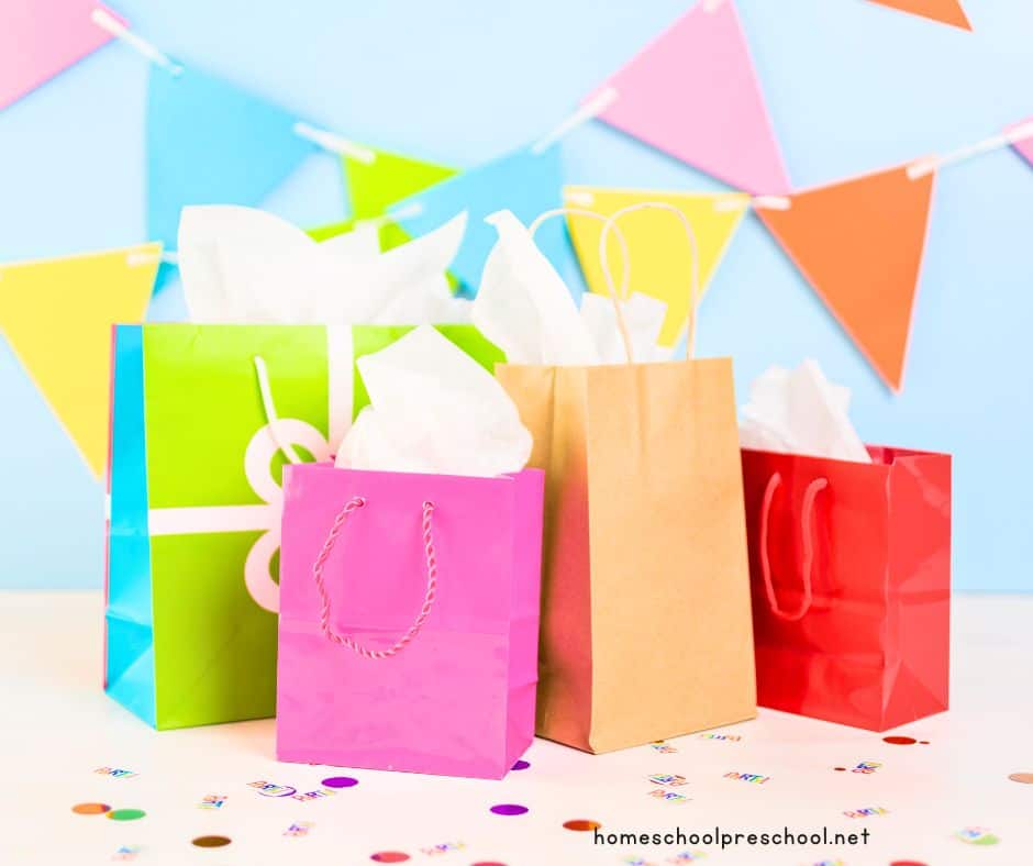 gift bags on table with confetti and a banner on the wall
