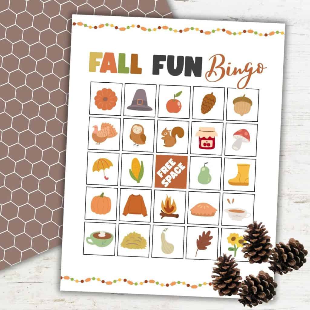 Fall Bingo game board for preschoolers featuring autumn-themed illustrations, displayed on a rustic background with pinecones and a festive border.
